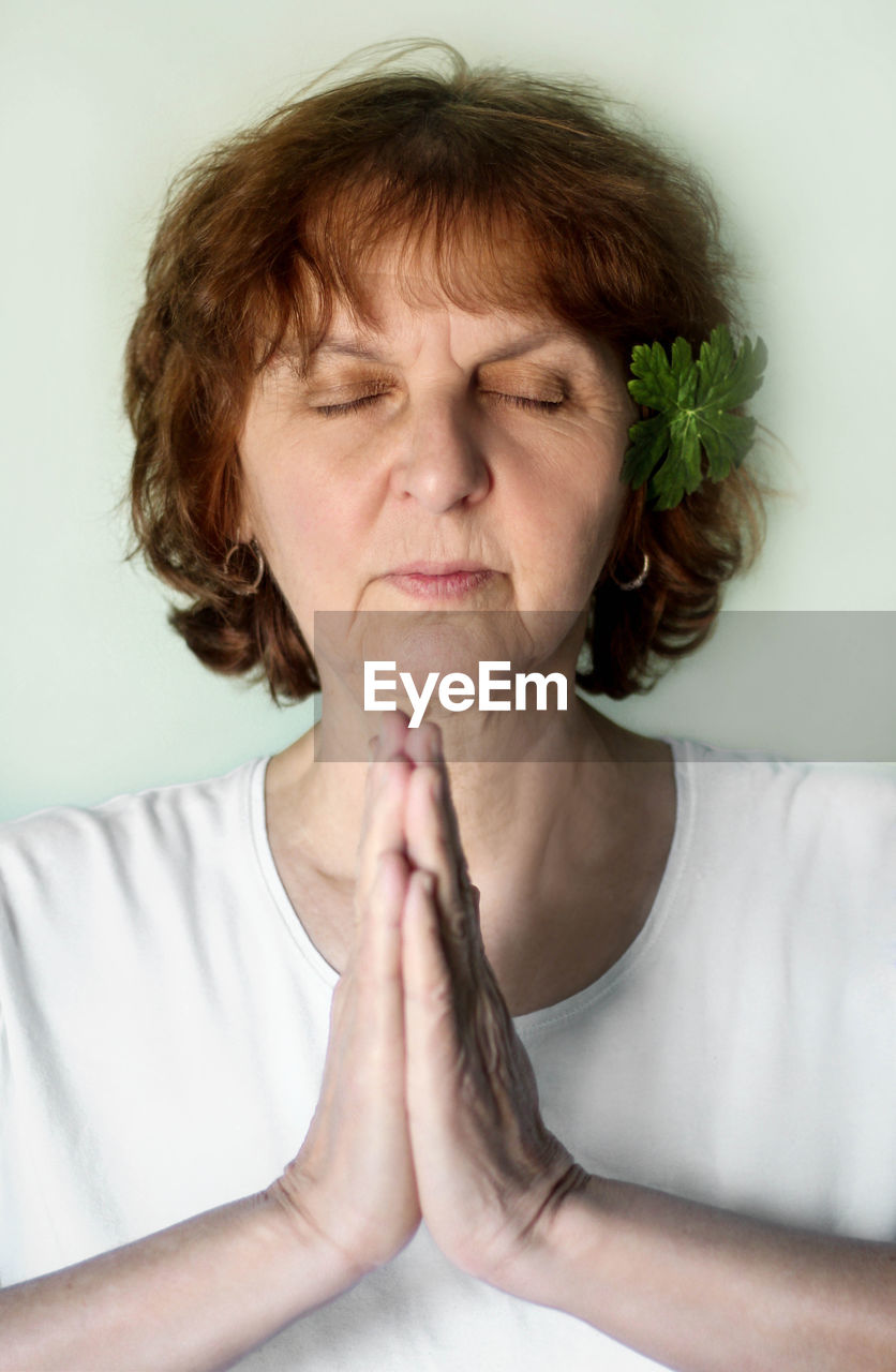 Close-up of woman with eyes closed meditating against white background
