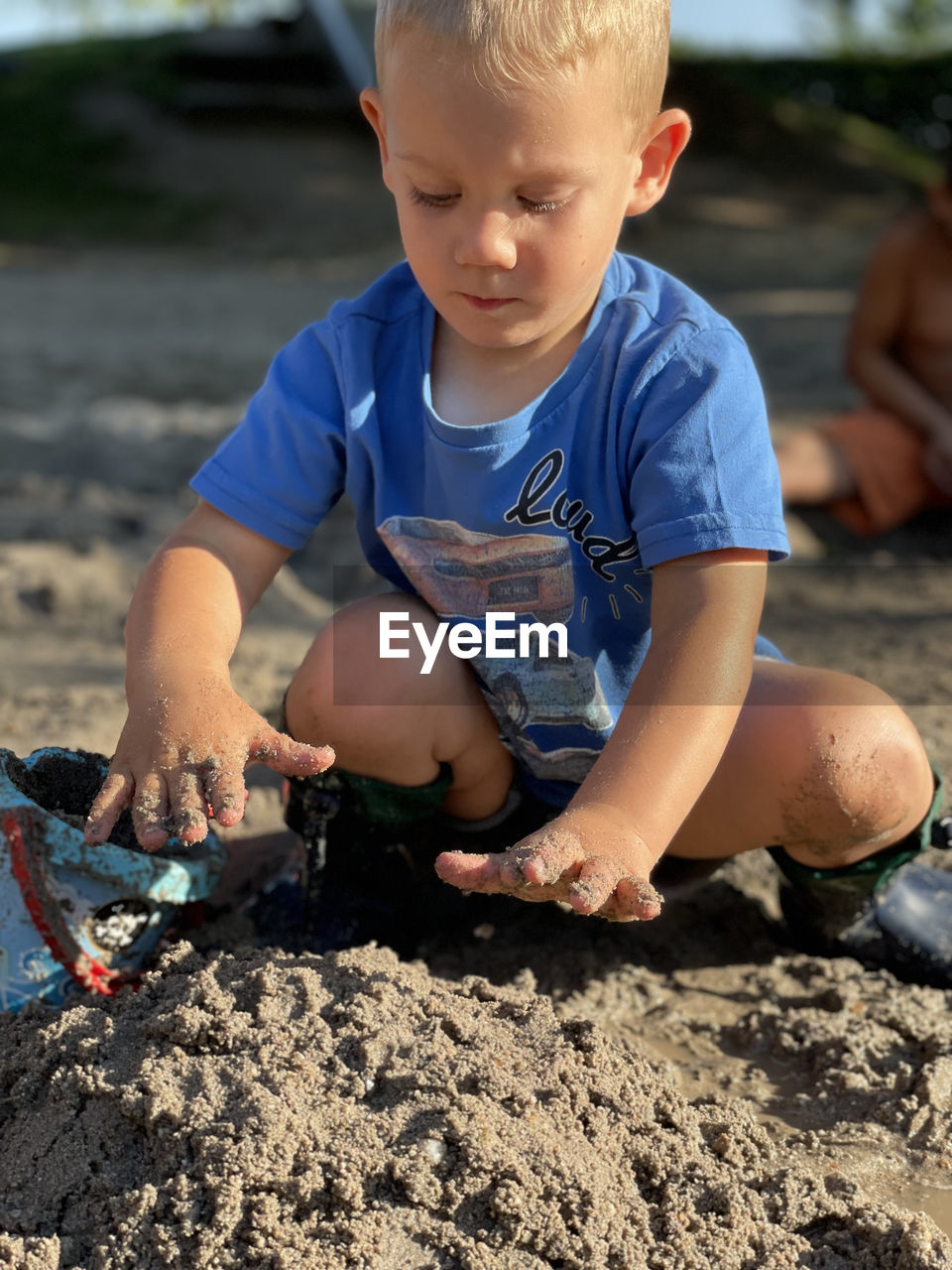 portrait of cute boy playing with sand at beach