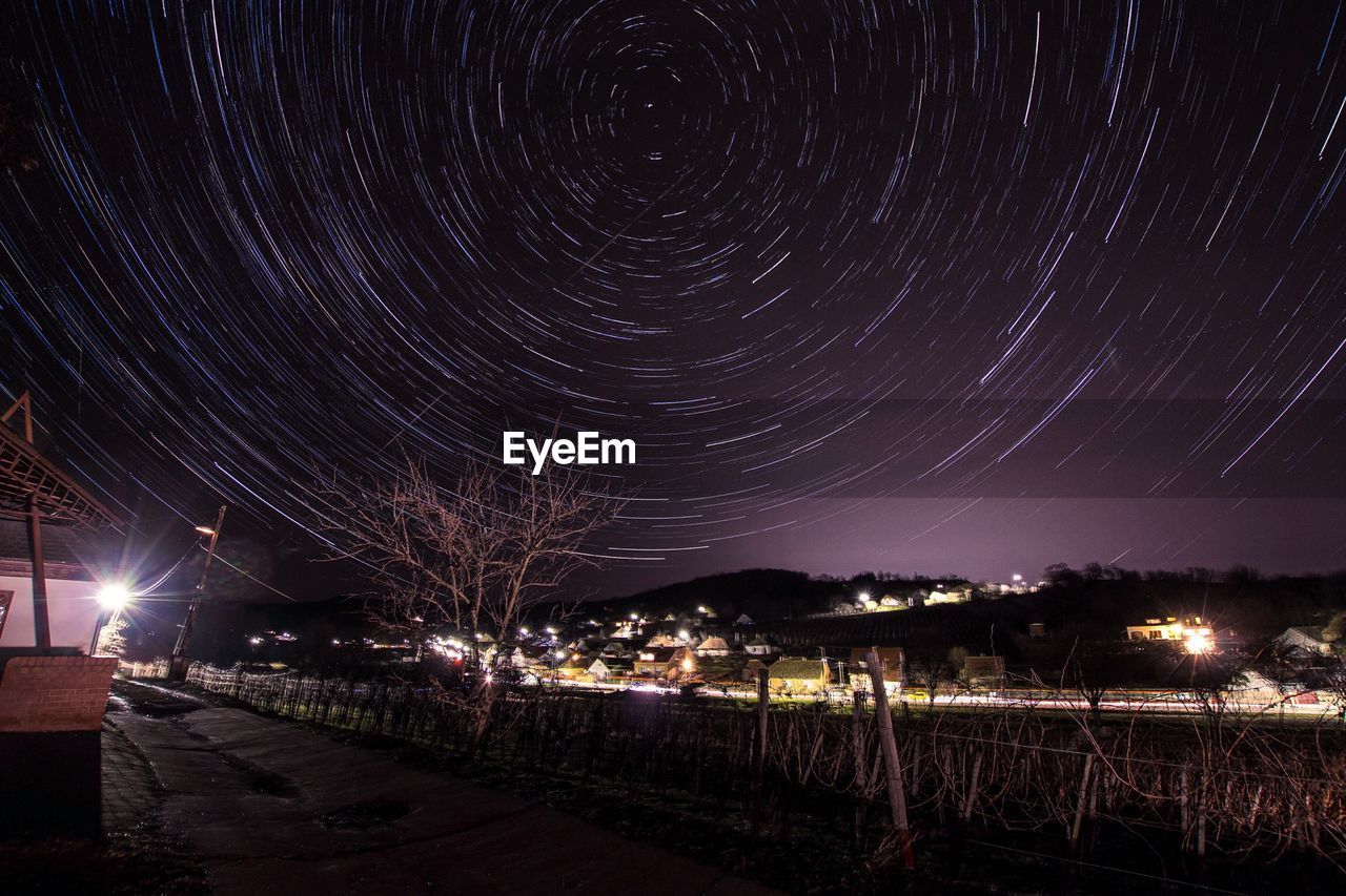 Scenic view of star trails over town