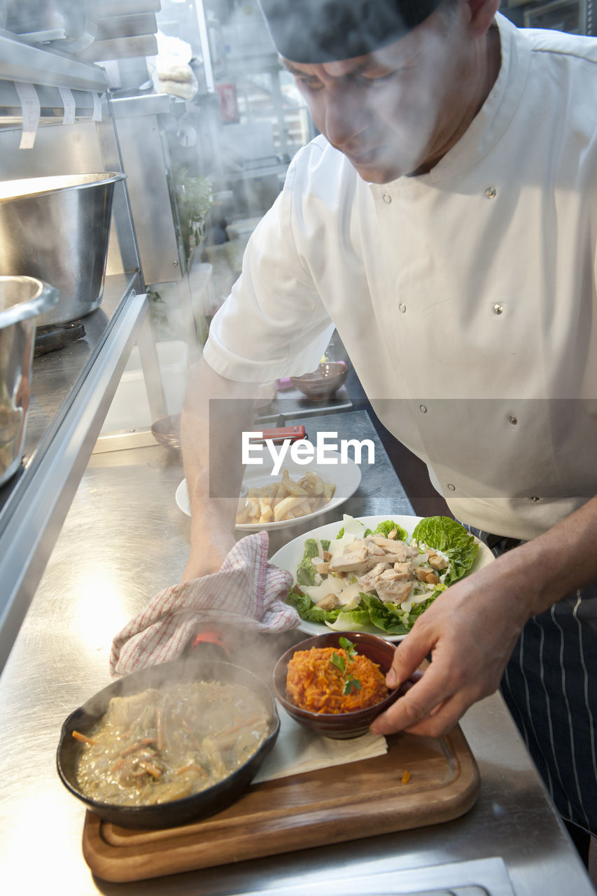 Chef preparing hot dish at commercial kitchen in british pub