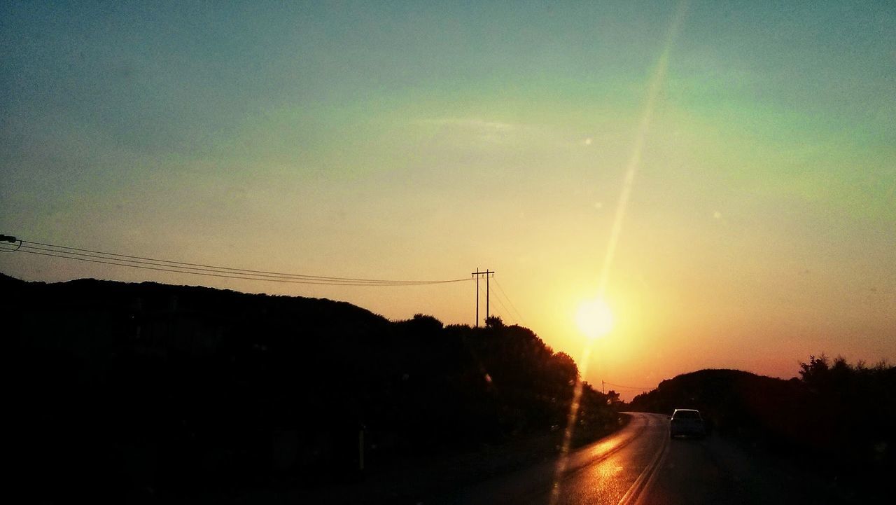 Empty country road along silhouette landscape at sunset