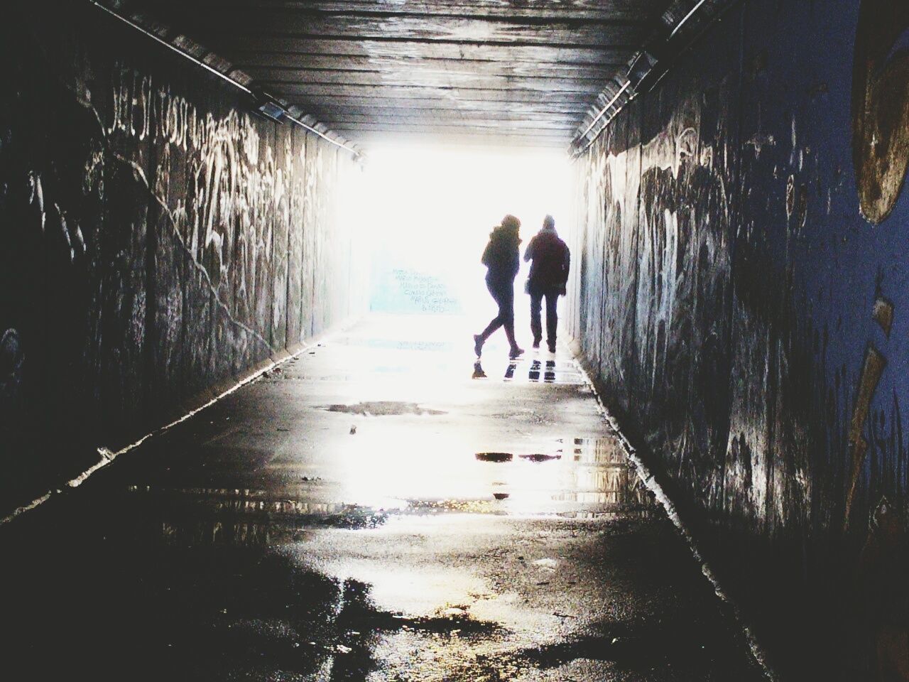 REAR VIEW OF FRIENDS WALKING IN TUNNEL