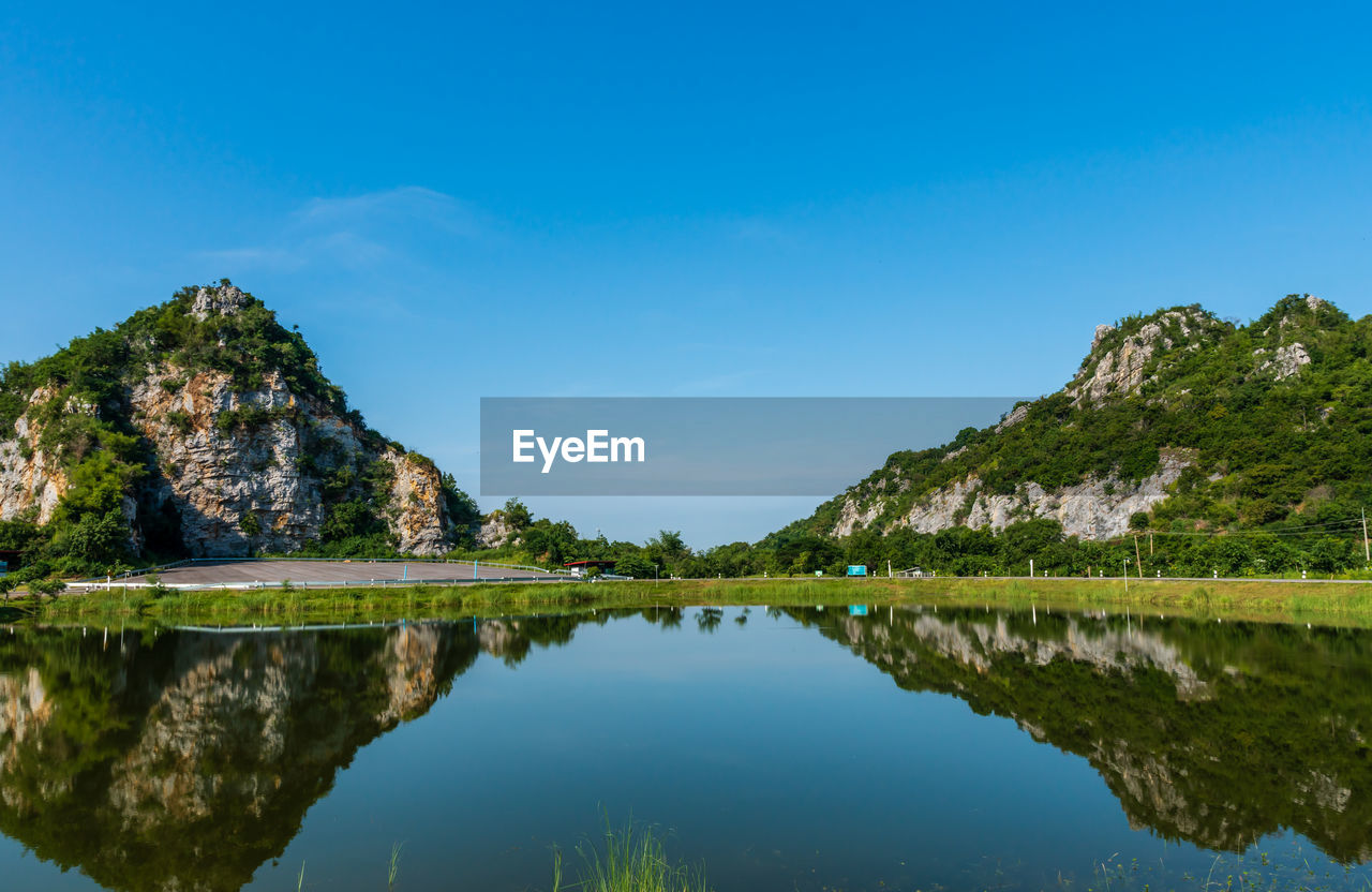 Scenic view of lake and mountains against blue sky