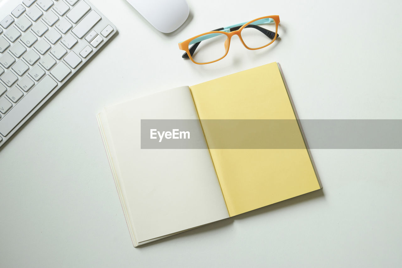 High angle view of open blank book by eyeglasses on table