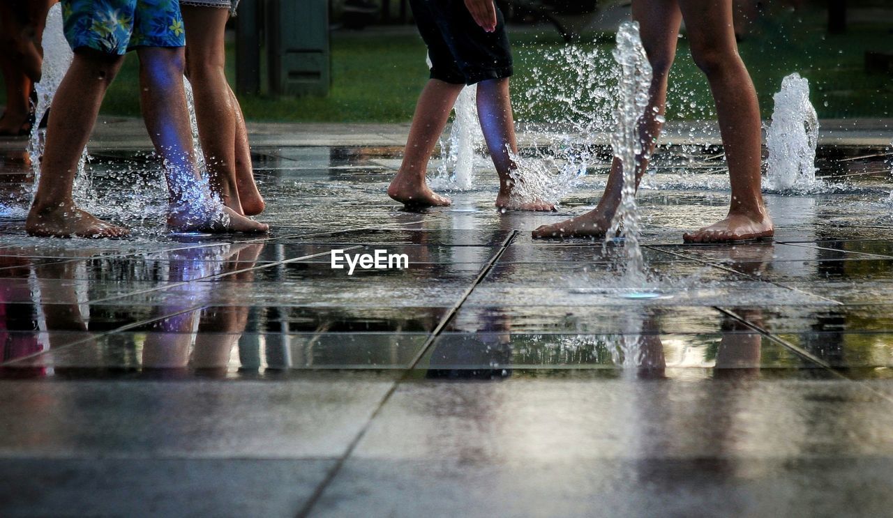 Low section of people standing on puddle