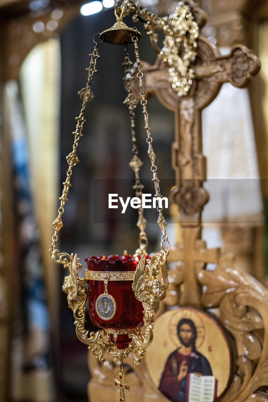 focus on foreground, hanging, no people, religion, jewelry, architecture, fashion accessory, close-up, history, belief, metal, chain, the past, gold, necklace, wealth, spirituality, selective focus