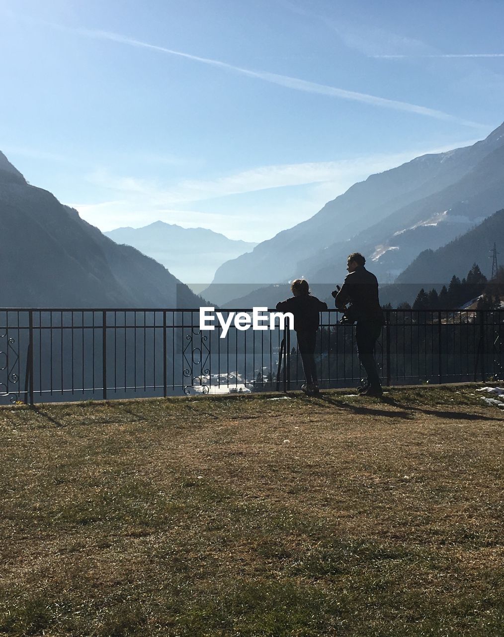 COUPLE STANDING ON MOUNTAIN ROAD AGAINST SKY