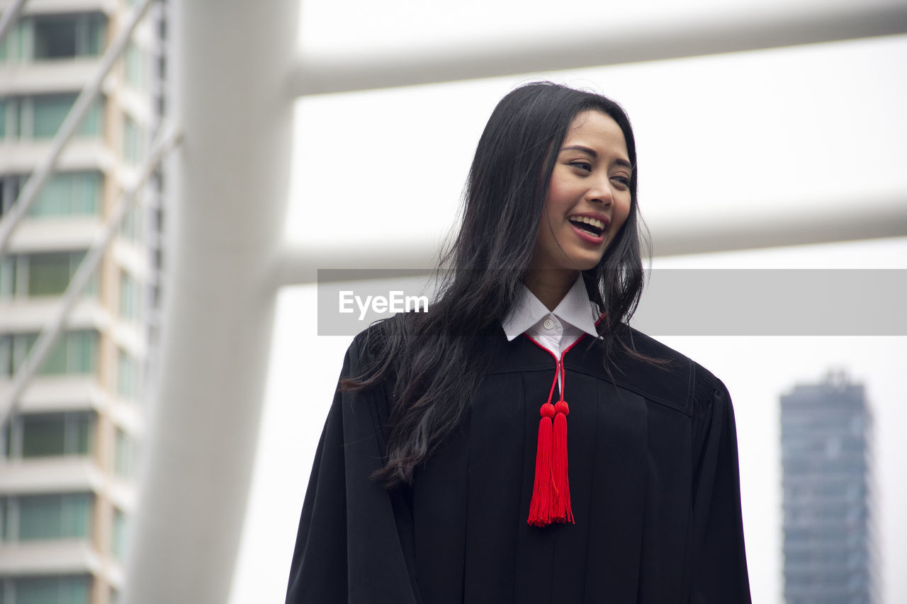 Smiling young woman wearing graduation gown