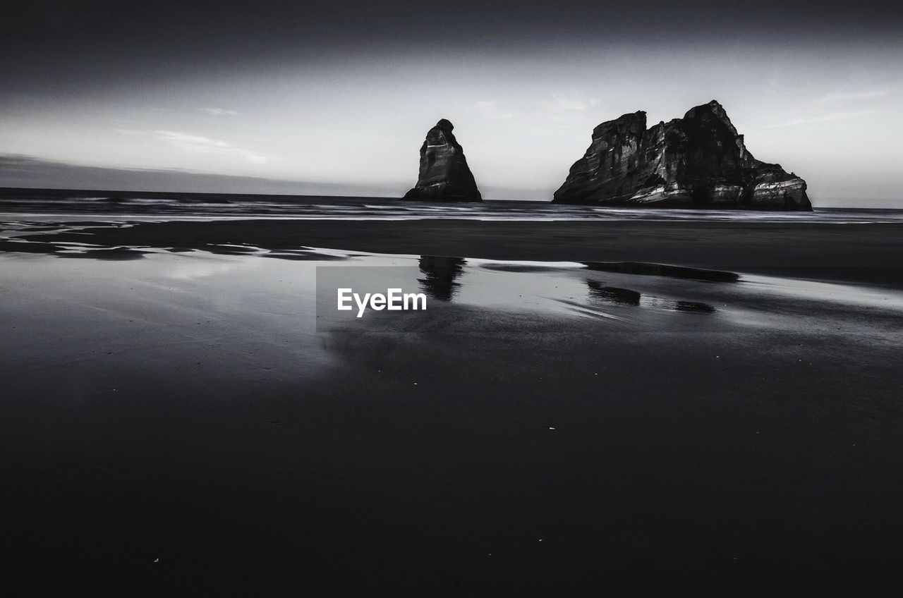 SCENIC VIEW OF ROCK FORMATIONS ON BEACH AGAINST SKY