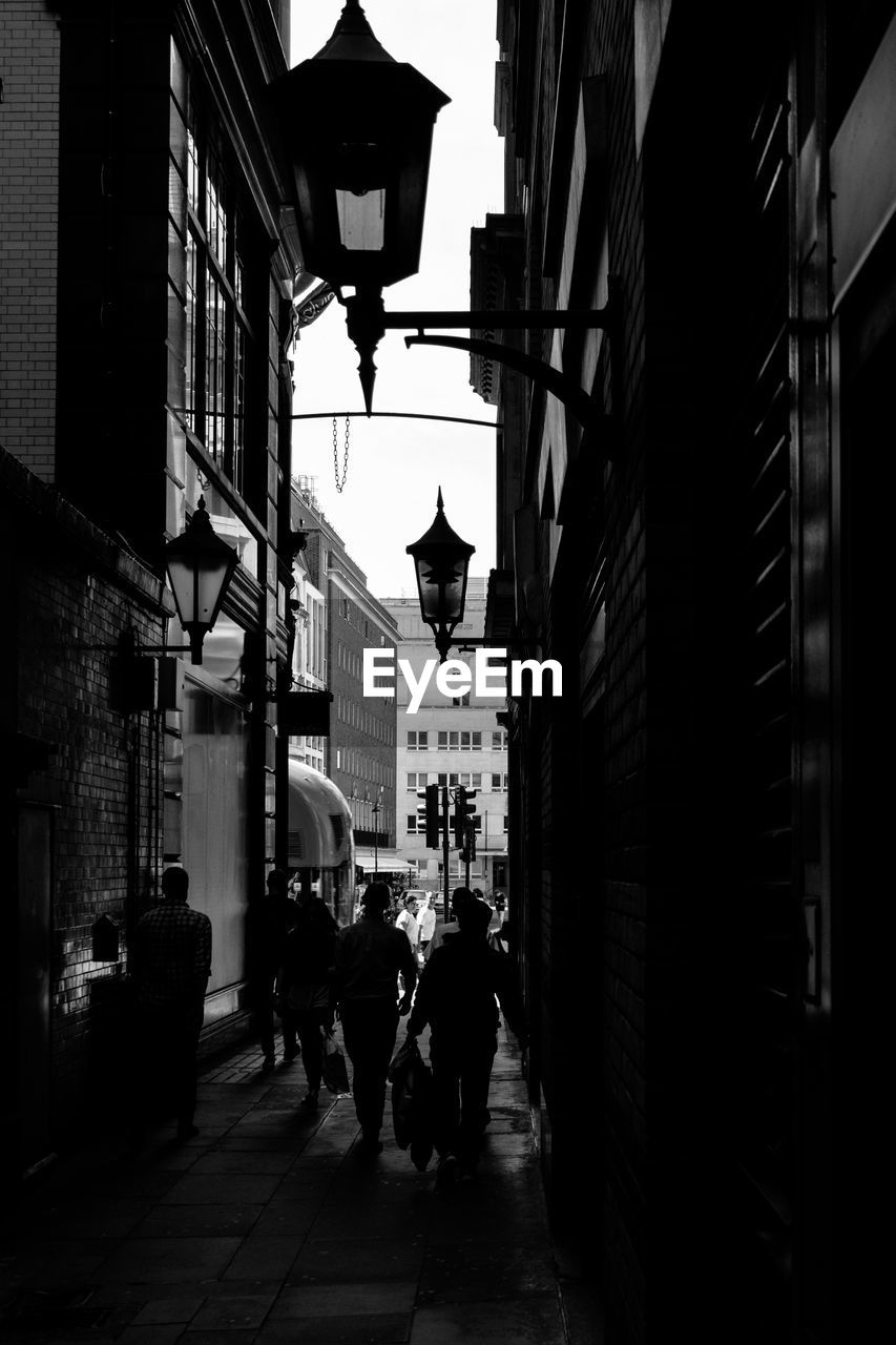 PEOPLE WALKING ON STREET AMIDST BUILDINGS