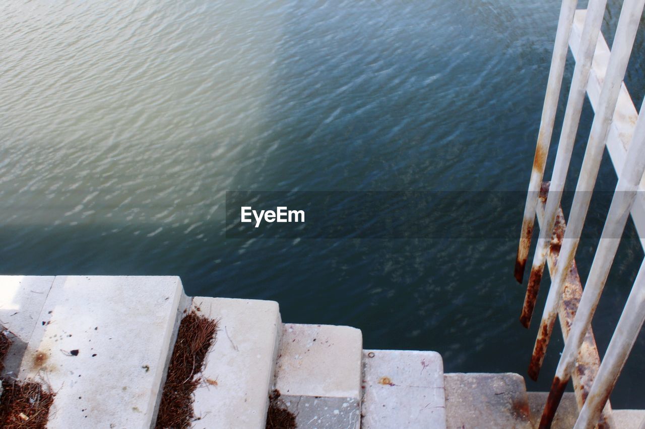 HIGH ANGLE VIEW OF METAL RAILING AGAINST SEA