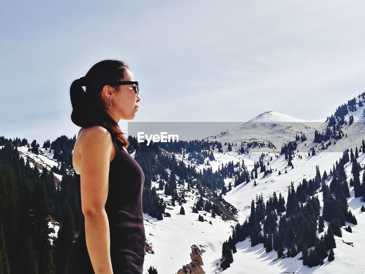 Side view of young woman looking at snow covered mountains