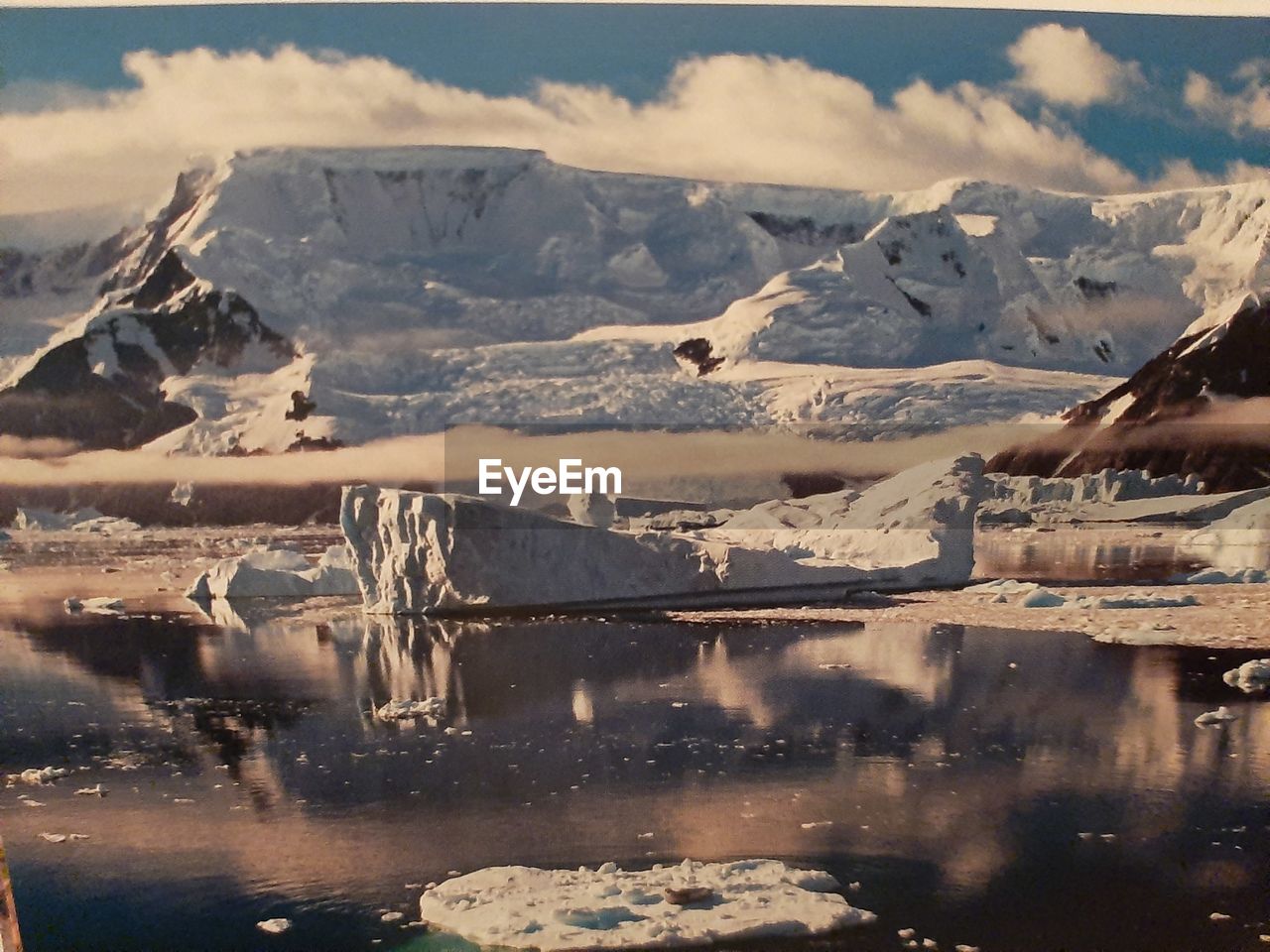 Scenic view of lake by snowcapped mountains against sky