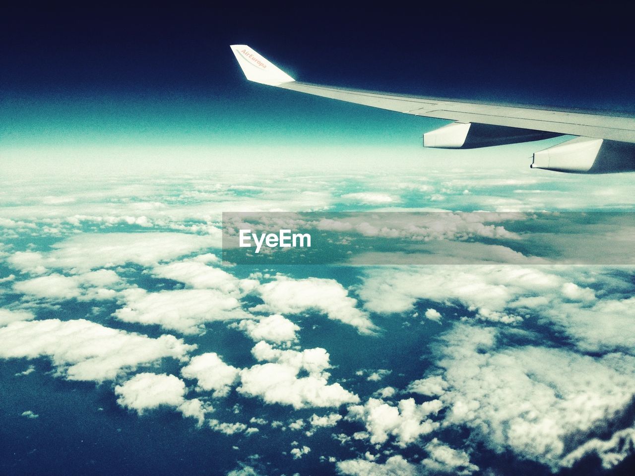 Cropped image of airplane flying above clouds in sky