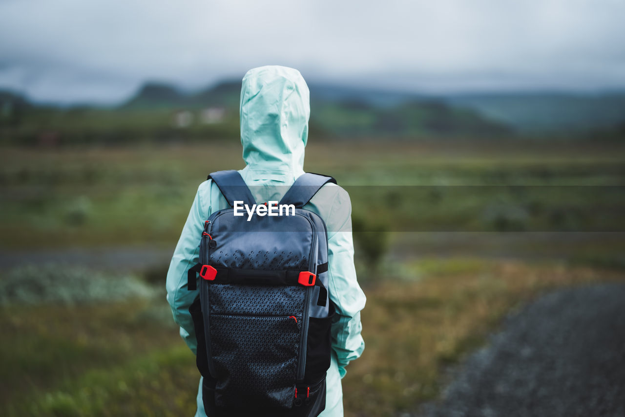 Woman with backpack and green jacket on travel in iceland