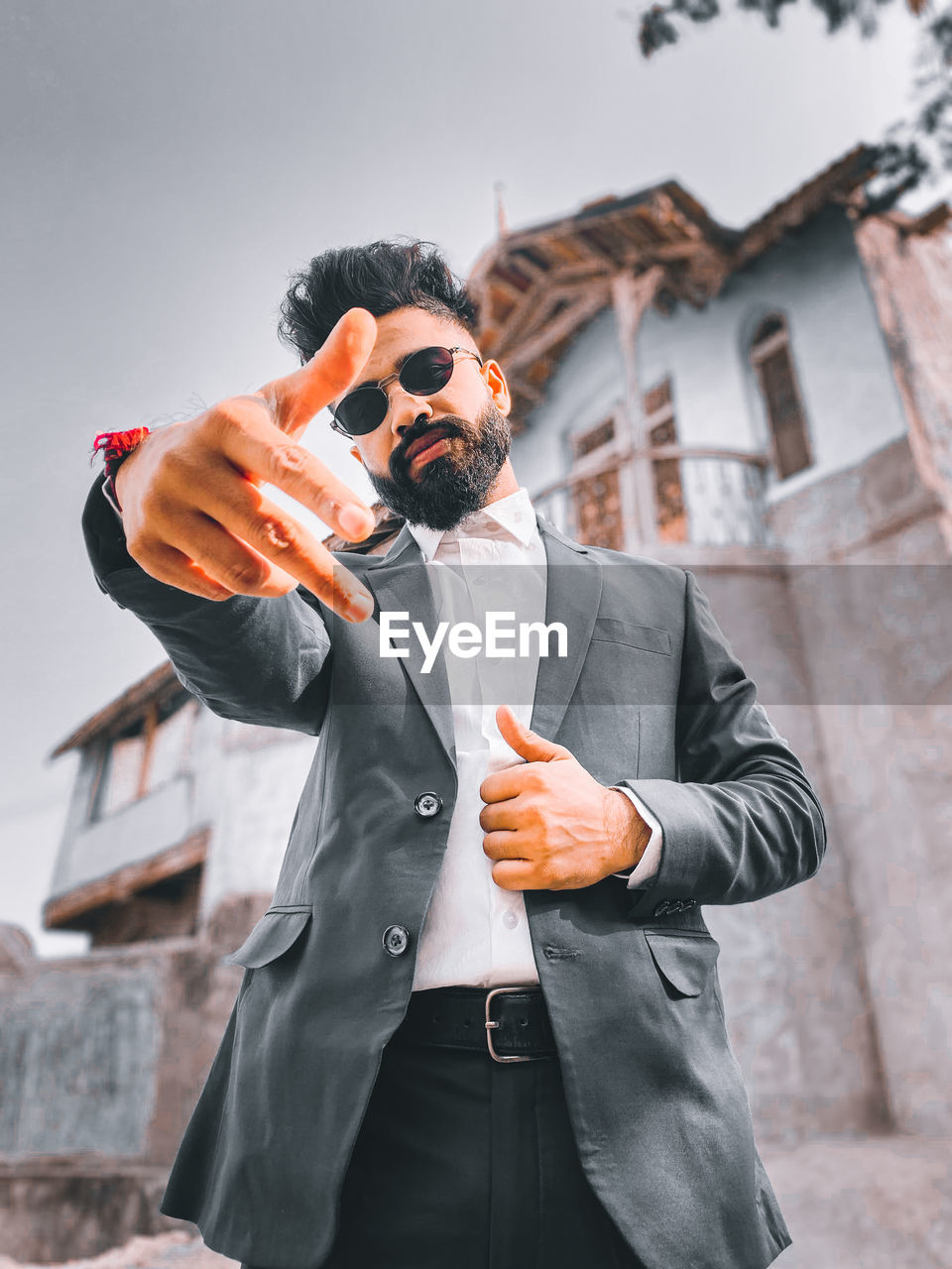 Portrait of young man wearing sunglasses while standing against wall