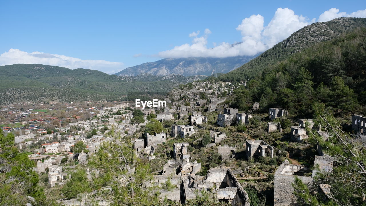 mountain, mountain range, landscape, sky, environment, architecture, scenics - nature, plant, nature, tree, land, building, building exterior, built structure, beauty in nature, no people, valley, travel destinations, residential district, village, cloud, walking, house, travel, city, day, outdoors, town, tourism, panoramic, blue, adventure, plateau, tranquility, rural scene, pine tree, forest, wilderness, tranquil scene, high angle view