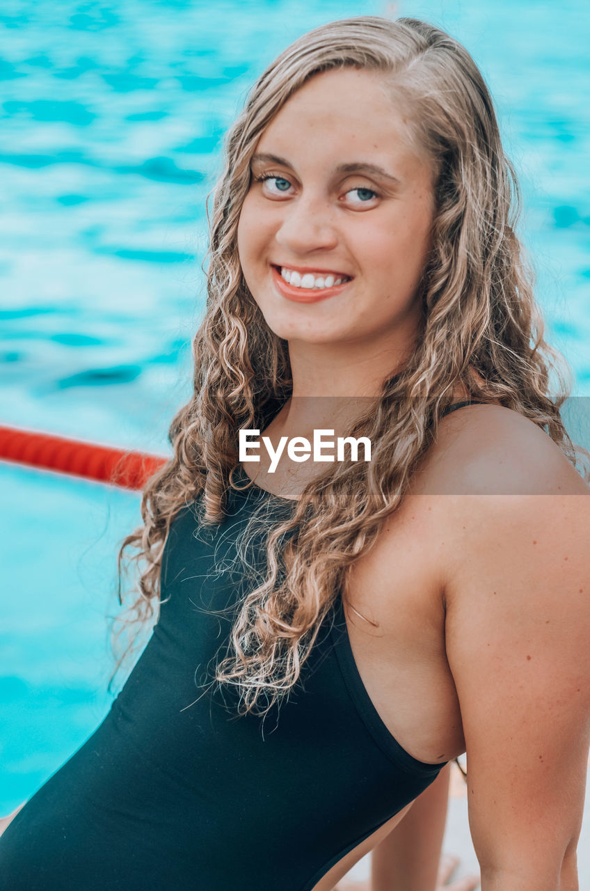 PORTRAIT OF BEAUTIFUL YOUNG WOMAN SWIMMING IN POOL