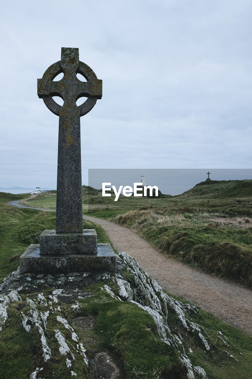 Cross on field against sky