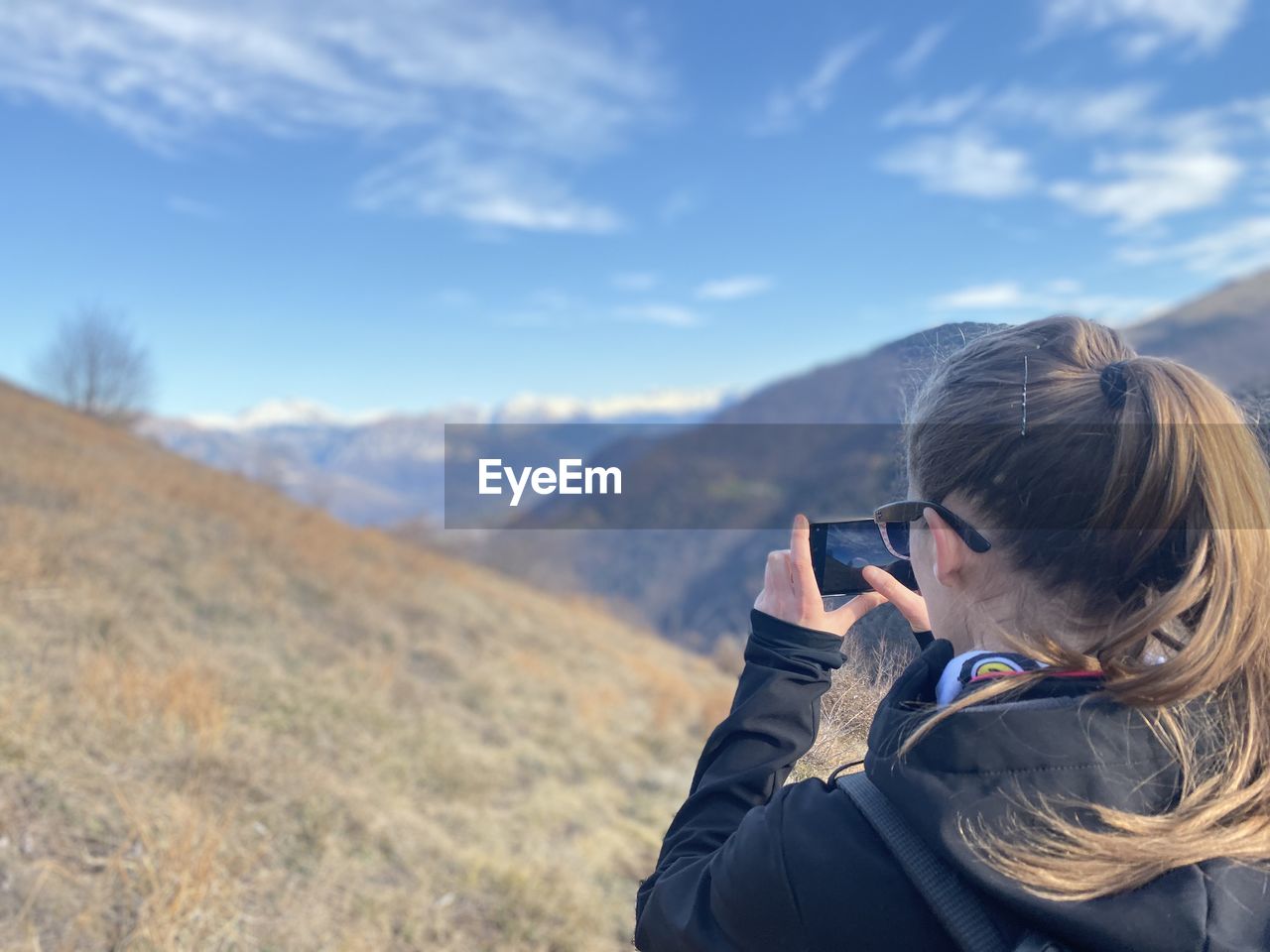 Rear view of woman photographing mountains