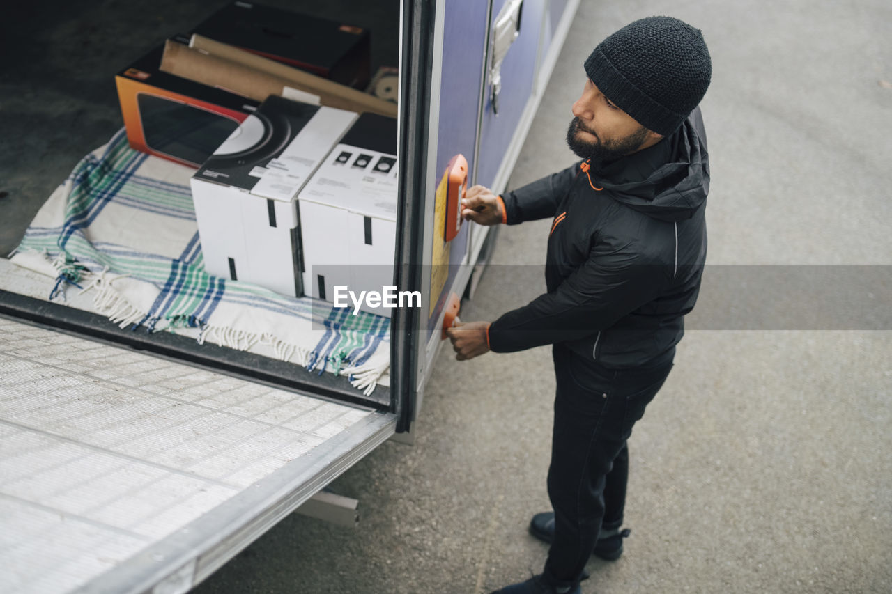 High angle view of worker opening van trunk by pushing buttons on street