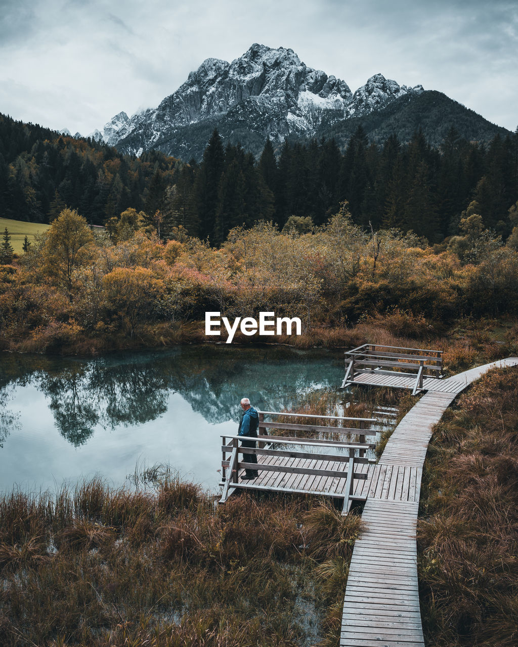 Senior man standing on pier by lake