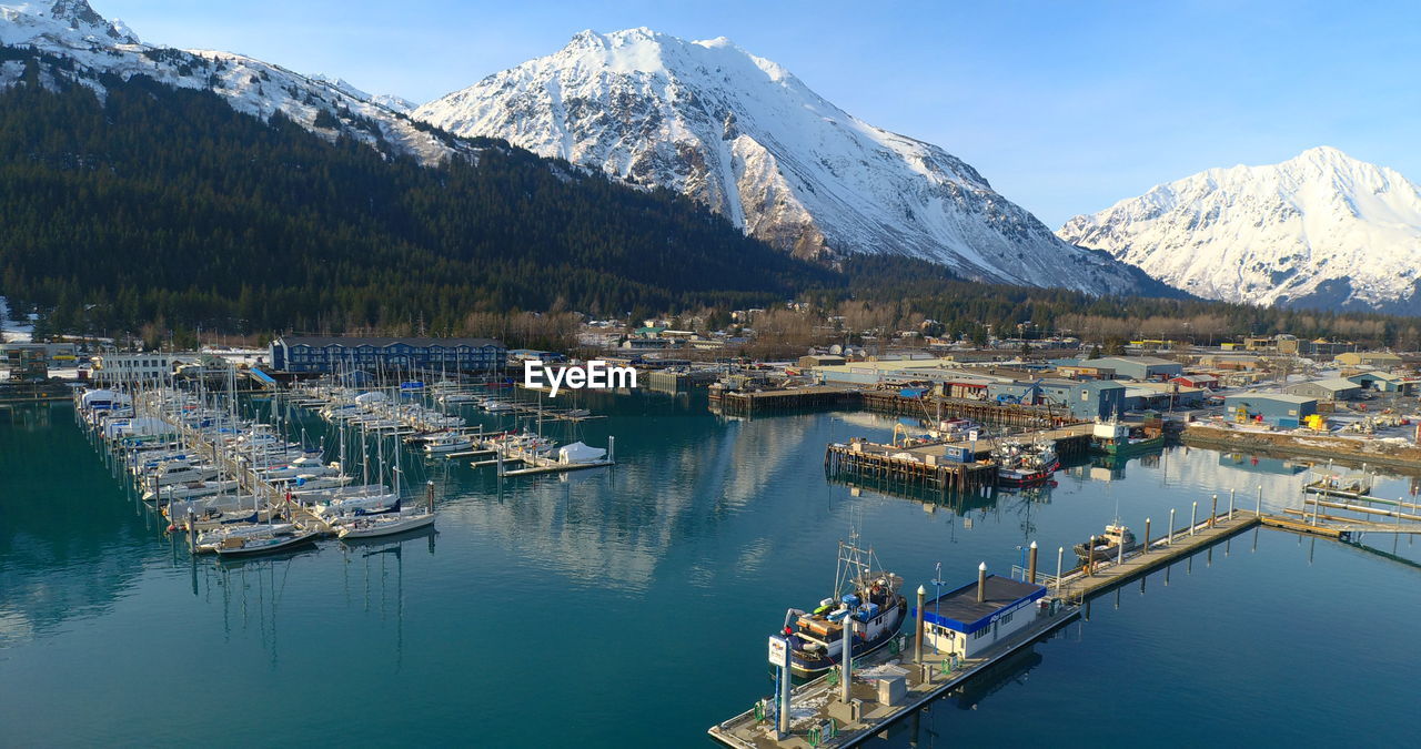 Sailboats moored at harbor against sky during winter