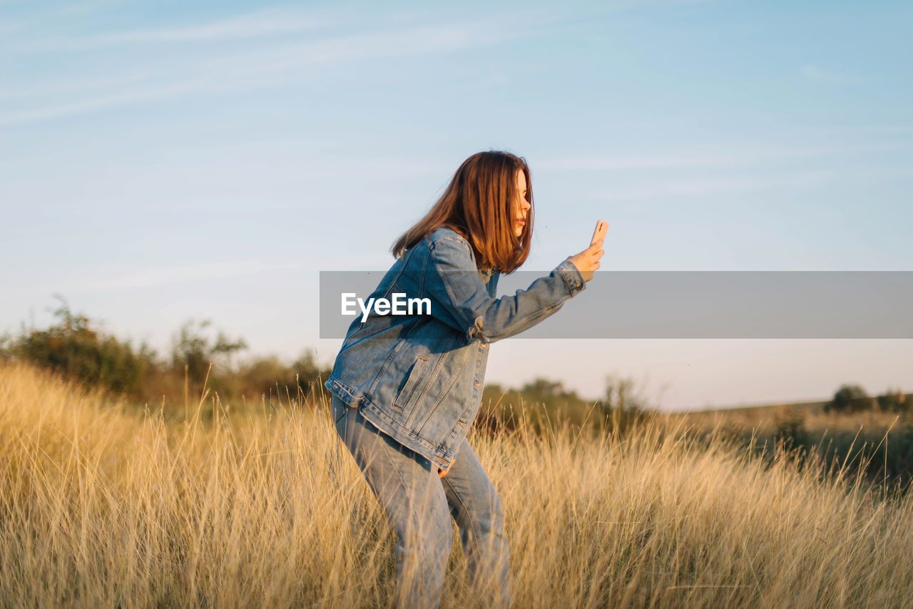 Side view of woman standing on field against sky