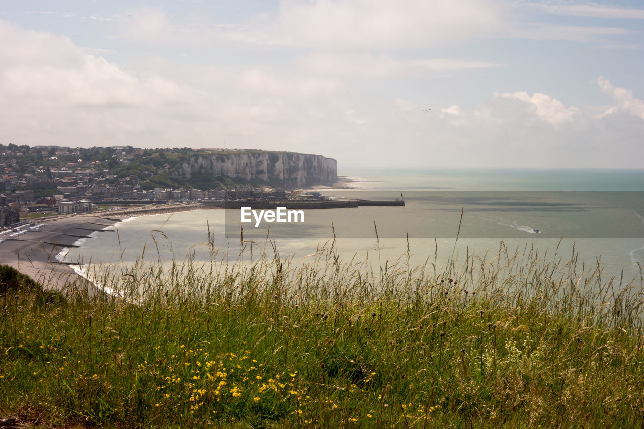 Scenic view of sea by cityscape against sky