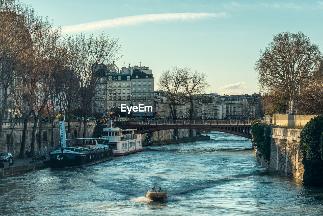 Bridge over river by buildings in city against sky