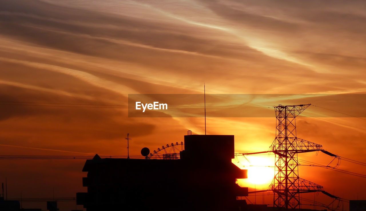 High section of silhouette built structure against sunset