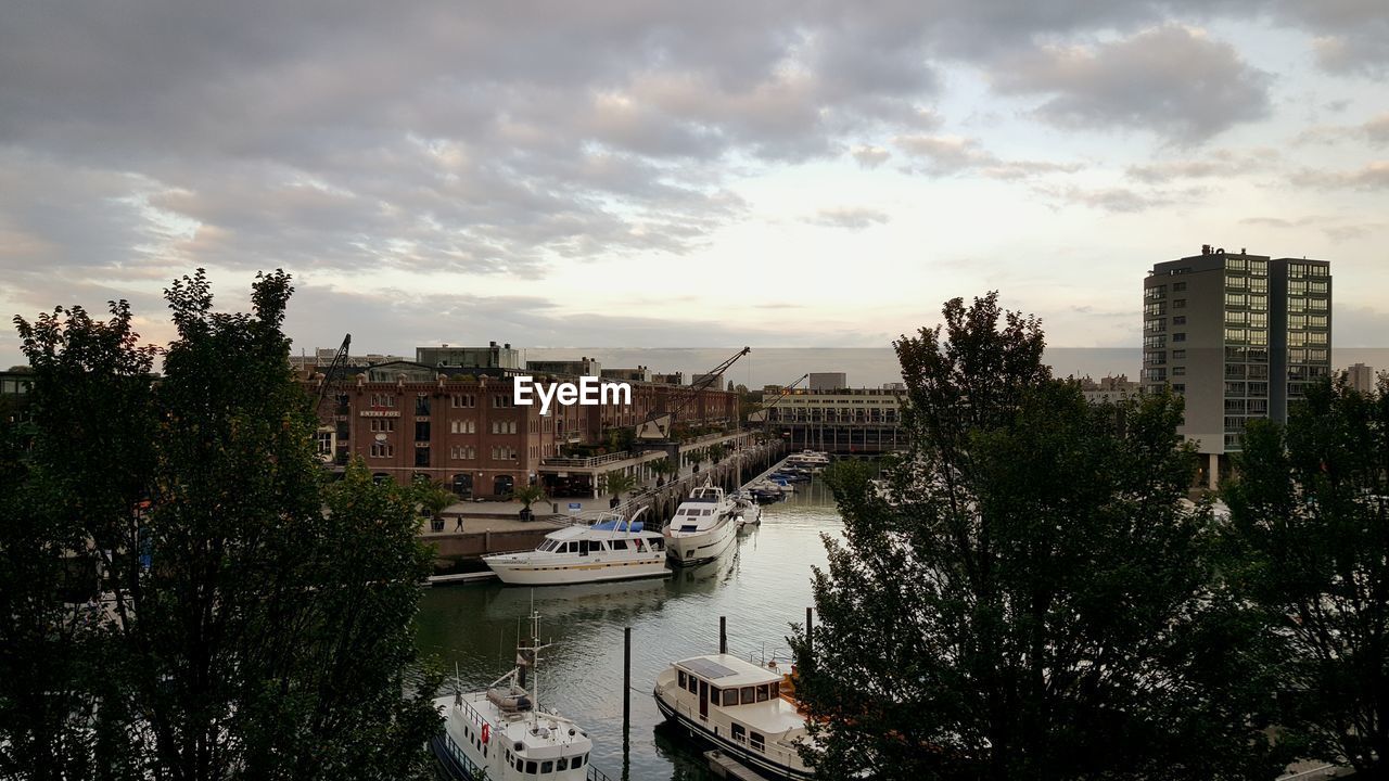 Boats on river amidst buildings against sky