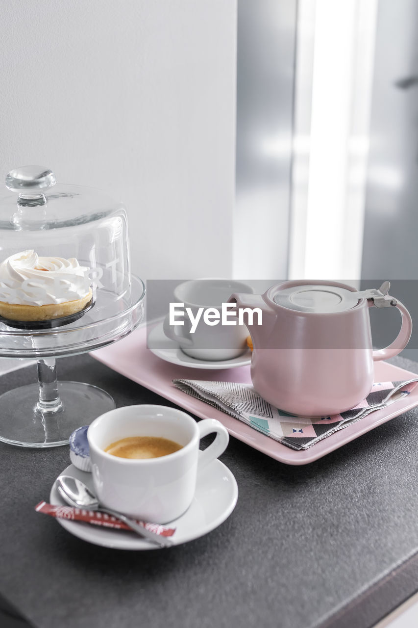 Coffee pot and cups setup on a tray and dessert cake in bright light mood - still life.