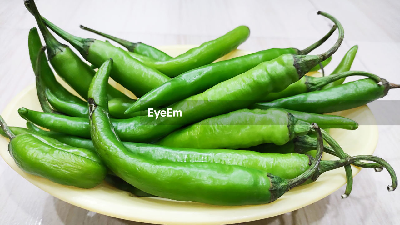 CLOSE-UP OF GREEN CHILI PEPPERS ON TABLE