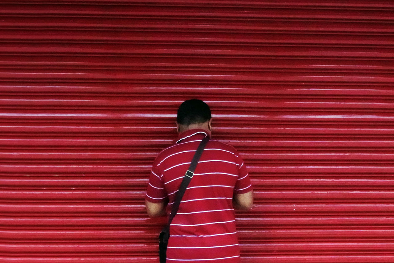 REAR VIEW OF BOY STANDING AGAINST RED LIGHT