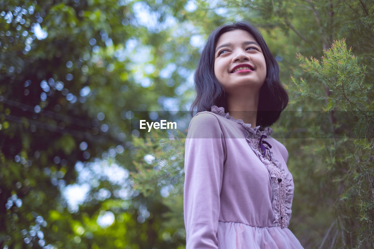 Low angle view of girl standing against tree