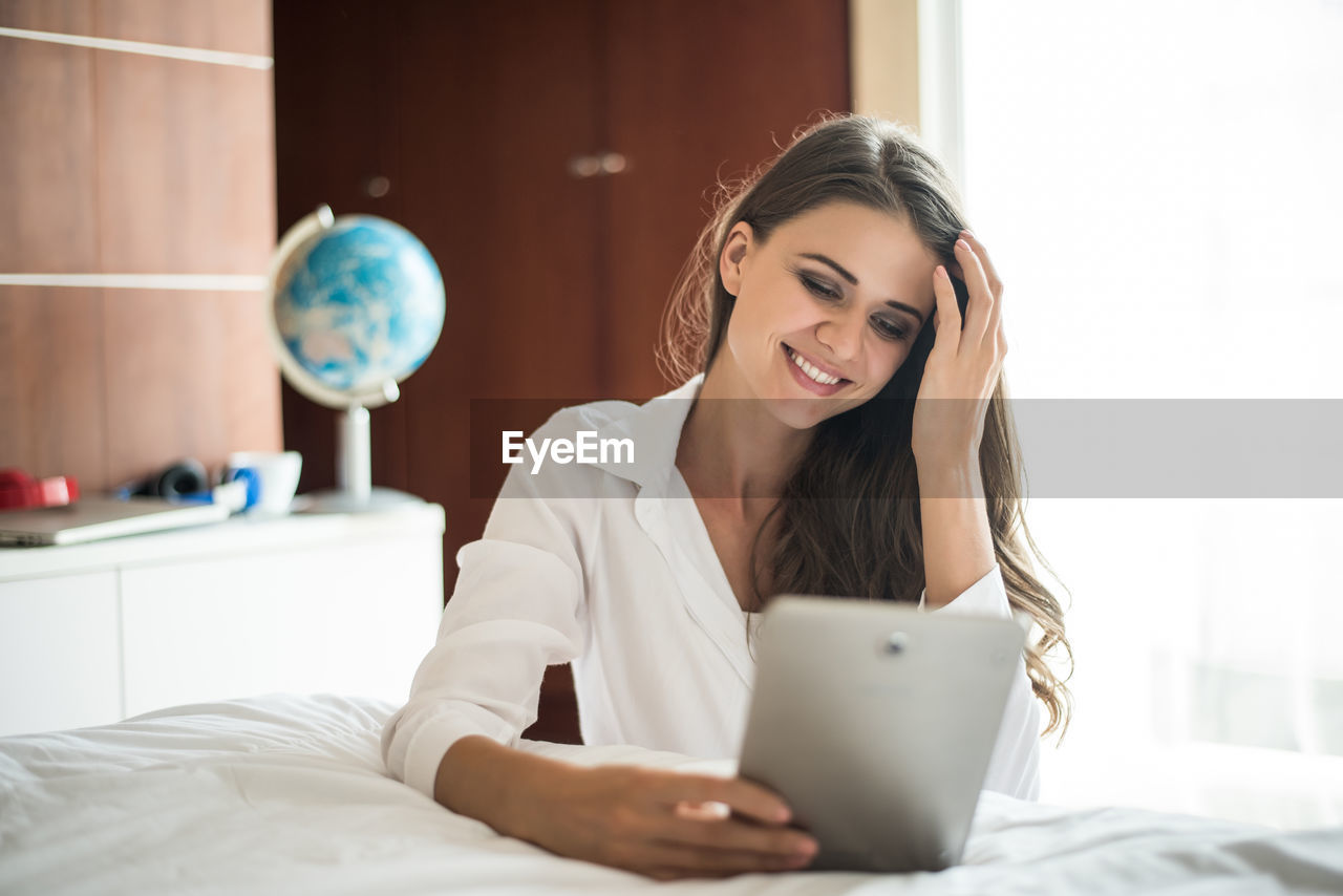 YOUNG WOMAN USING PHONE ON BED