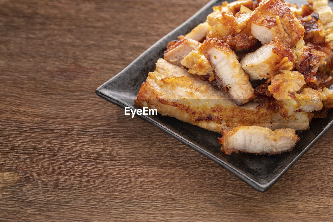 Tasty slice fried pork in rectangular ceramic plate on rustic natural wood texture background