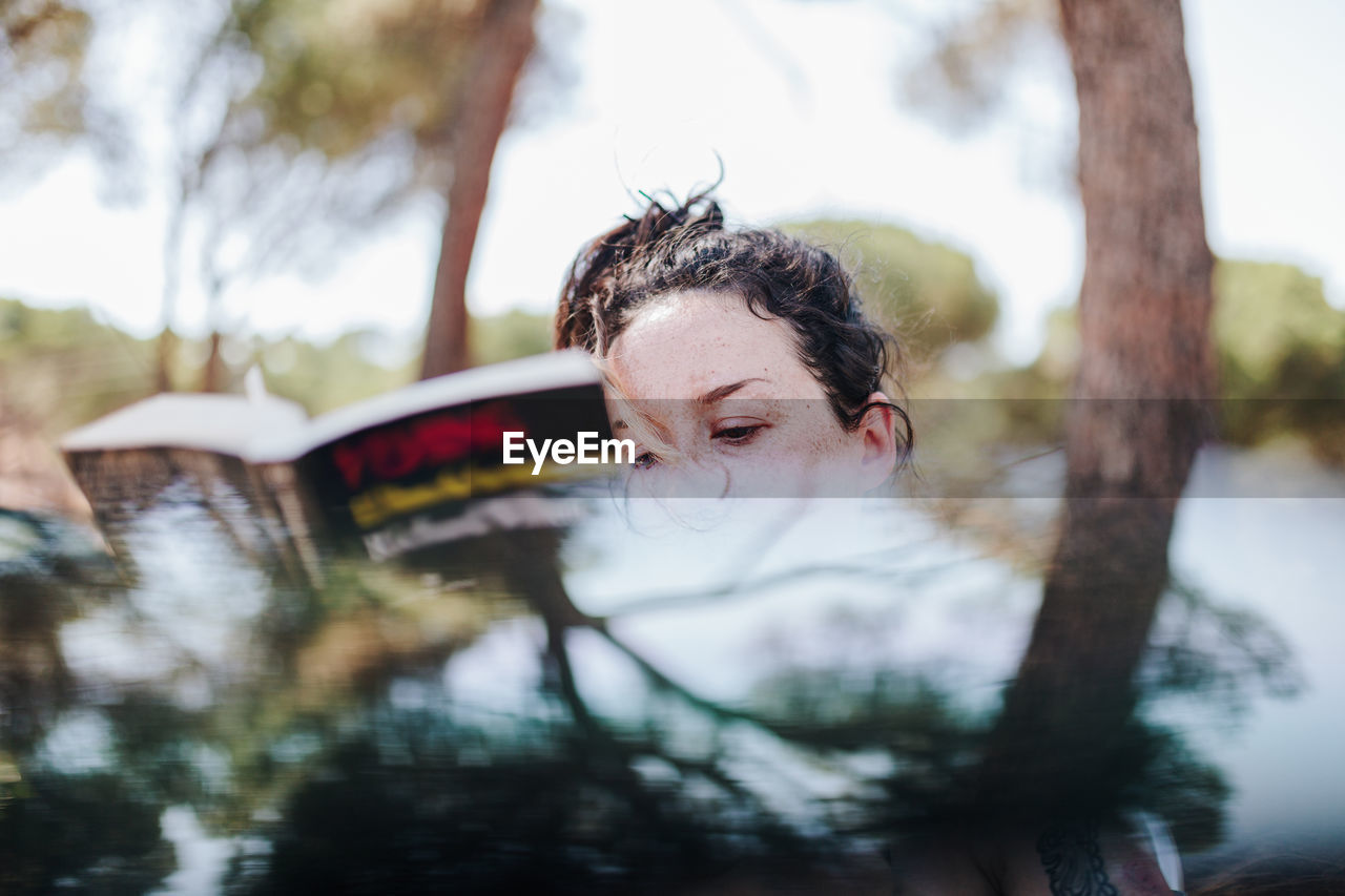 Portrait of woman with reflection of trees in water