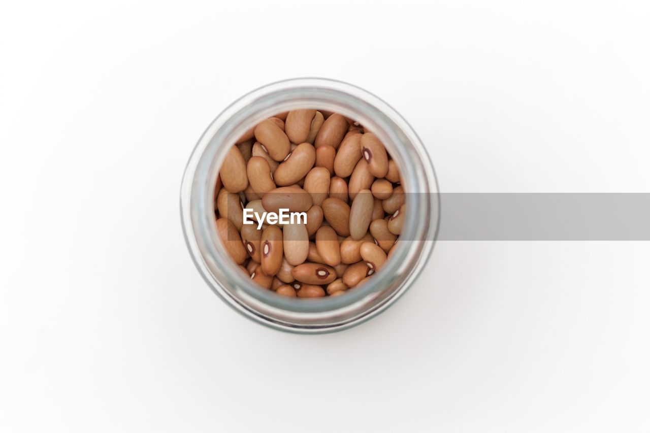 High angle view of beans in jar against white background