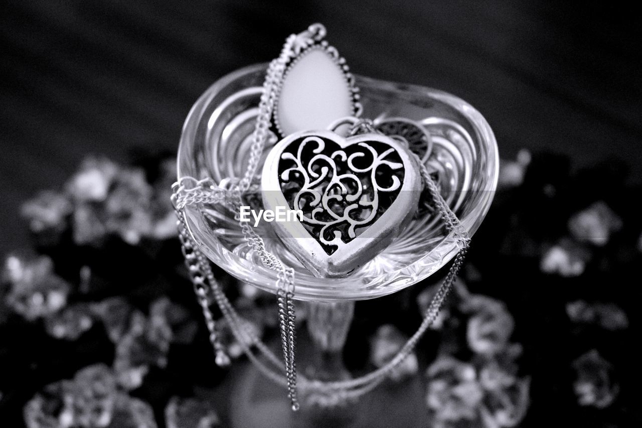 High angle view of glass on table filled with jewelry 