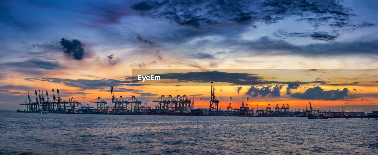 SILHOUETTE CRANES AGAINST SKY DURING SUNSET