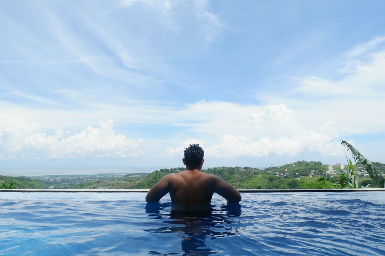 Rear view of man in swimming pool against sky