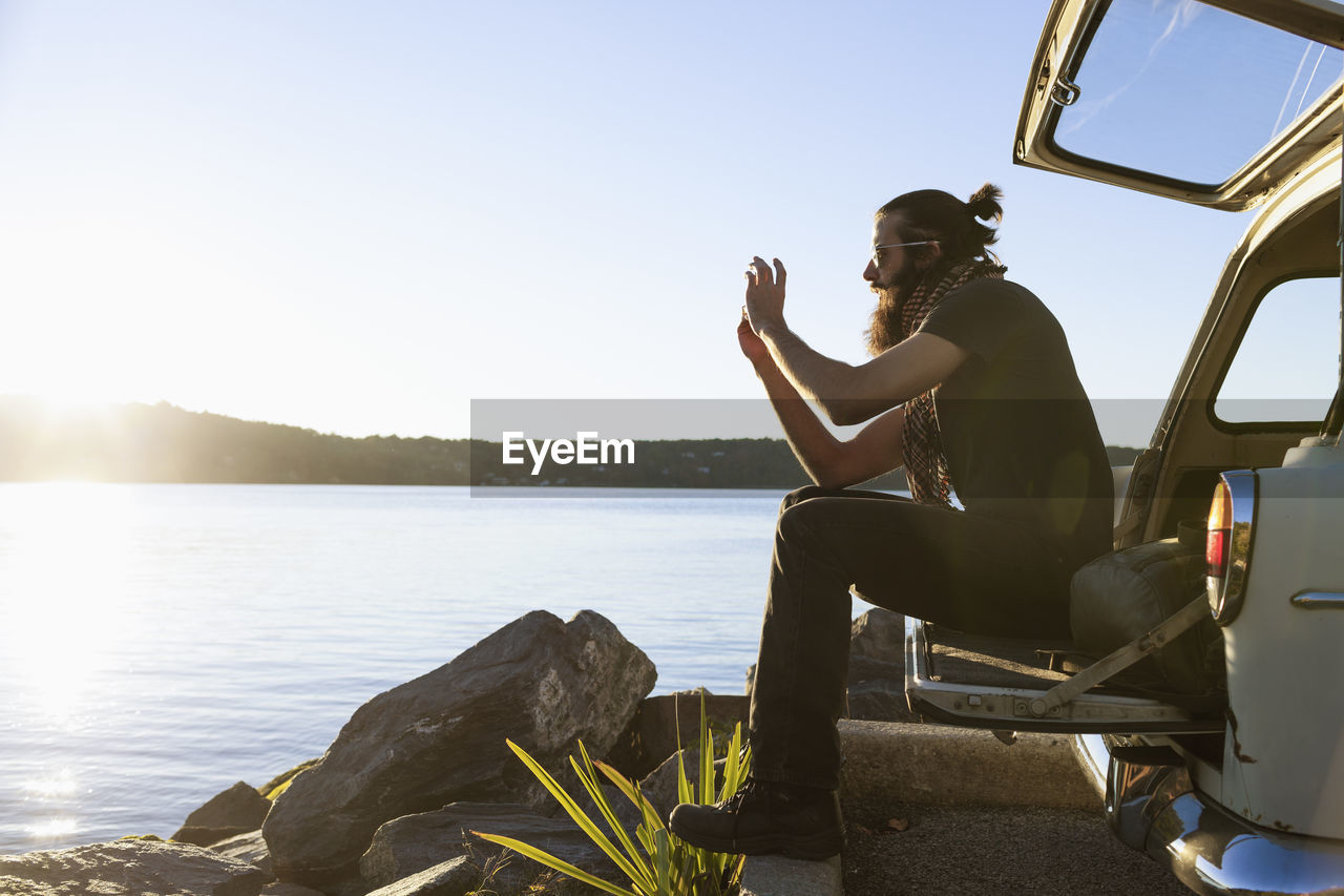 Young man taking a photograph of a scenic lake