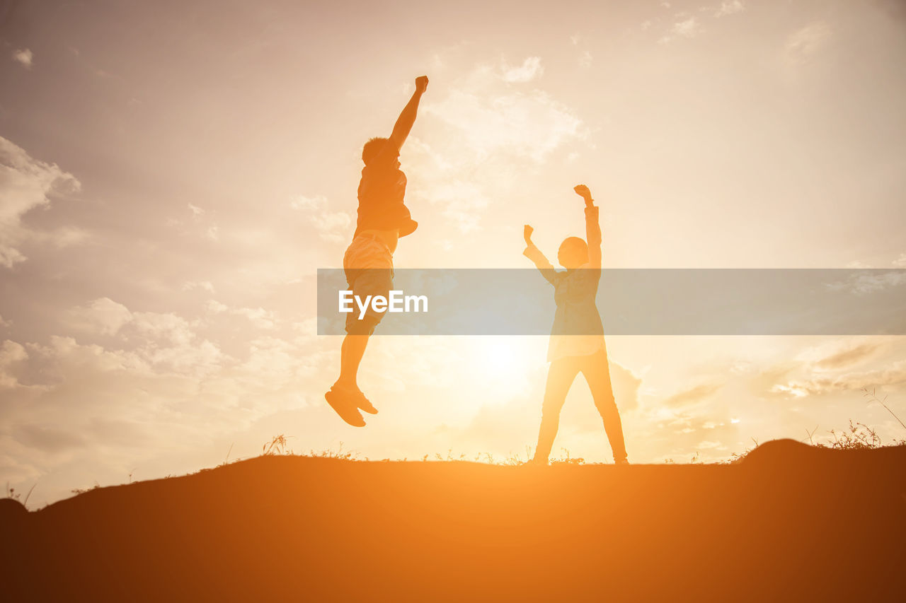 LOW ANGLE VIEW OF PEOPLE AT BEACH DURING SUNSET