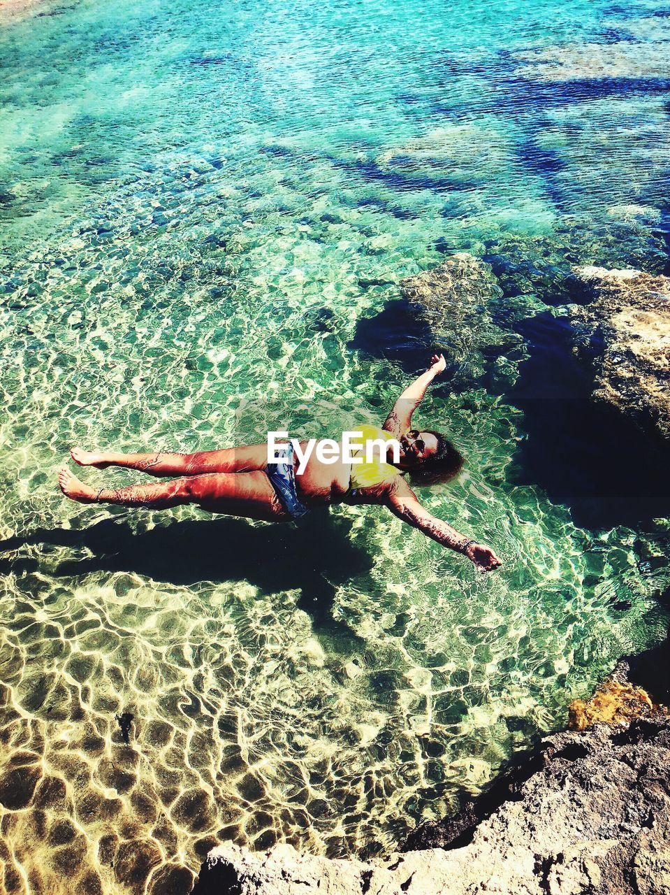 High angle view of smiling young woman swimming in sea