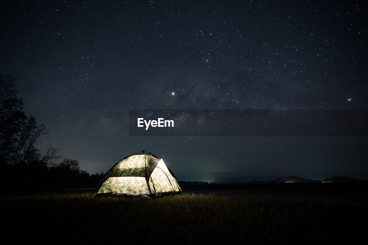 Scenic view of illuminated field against sky at night