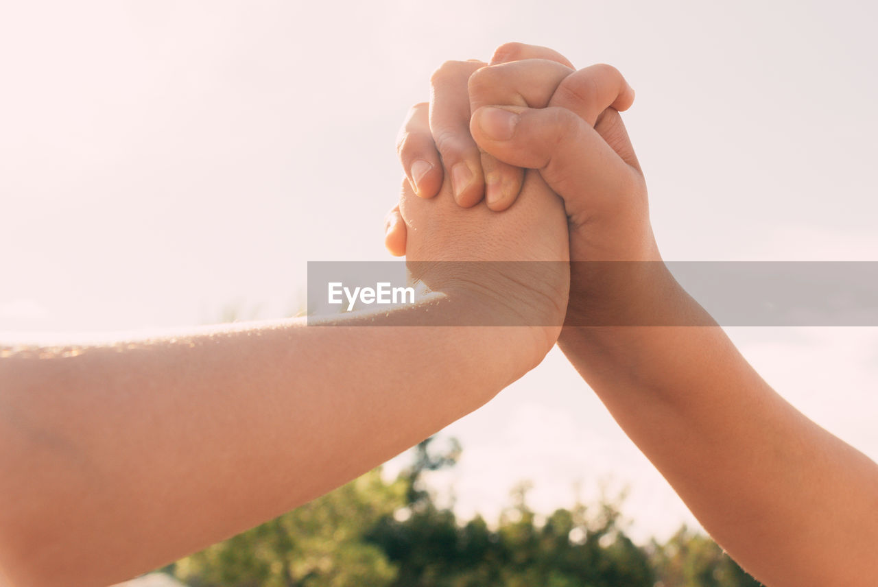 Union of intertwined hands two sisters in the background of the blue sky, family