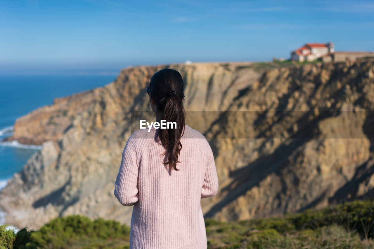 Rear view of woman looking at rock