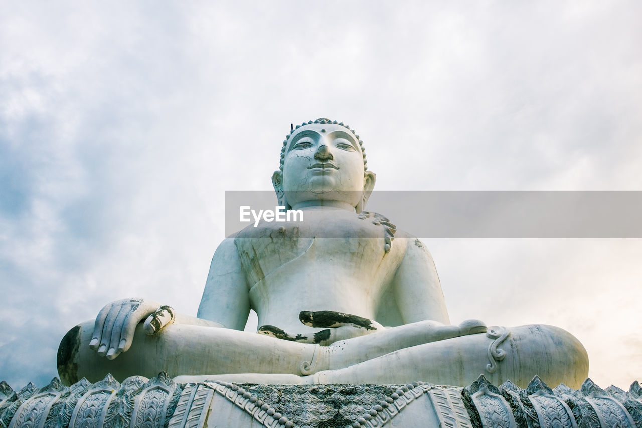 Low angle view of buddha statue against sky